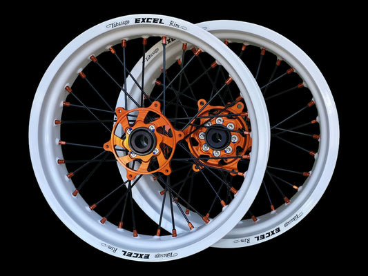 Supermoto Felgensatz 17 Zoll Excel RAL 9016 Verkehrsweiß mit G2 Pro Nabe Orange – vorne und hinten, schwarzer Hintergrund